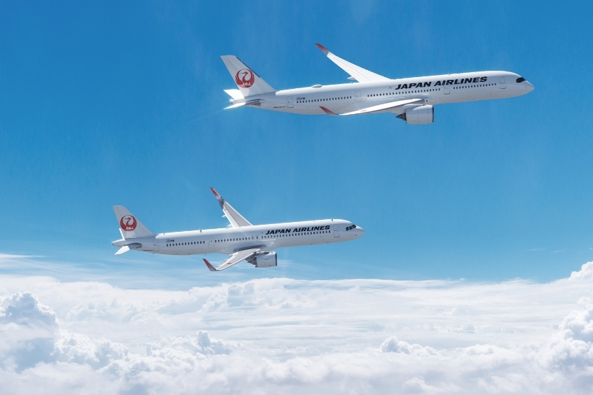 Máy bay Japan Airlines với sắc trắng trang nhã và biểu tượng chim hạc đỏ bay lướt dưới bầu trời 
