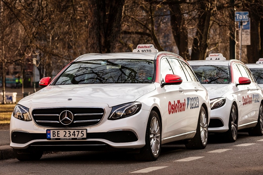  Taxi Mercedes-Benz của dịch vụ OsloTaxi đang đỗ trên đường phố Oslo, chuẩn bị phục vụ hành khách.