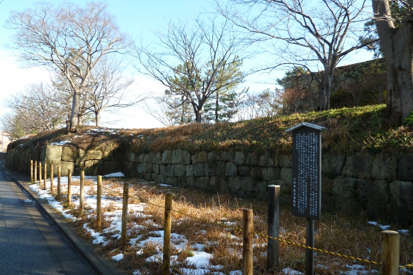 Cảnh quan thành Komatsu Nhật Bản với tường đá và cây cối xung quanh trong mùa đông.