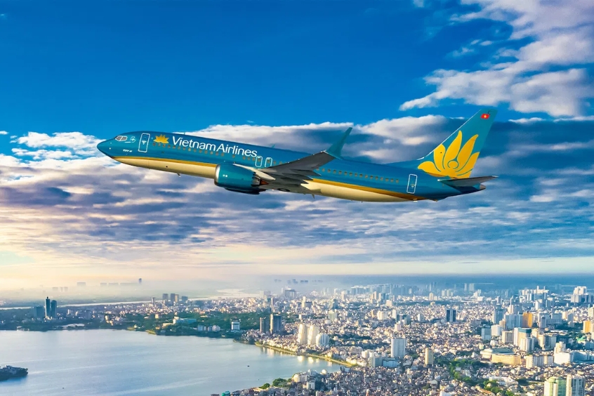 Máy bay Vietnam Airlines cất cánh trên bầu trời, với thành phố Hà Nội phía dưới.