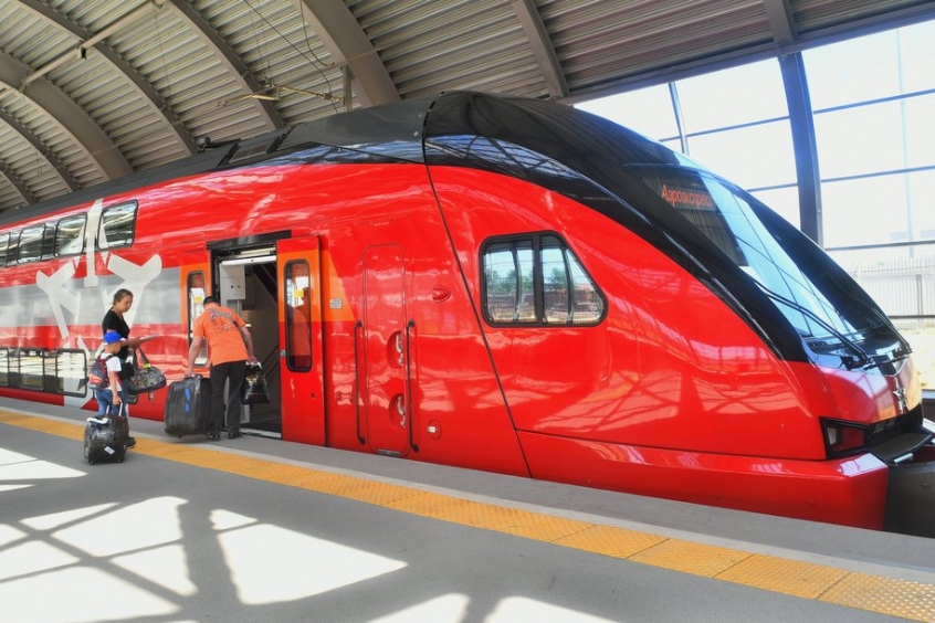 Tàu điện cao tốc màu đỏ đang đón khách tại ga, chuẩn bị di chuyển.