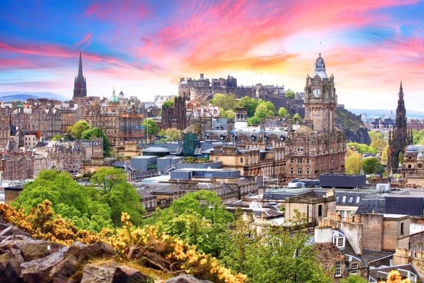 Thành phố Edinburgh vào hoàng hôn với lâu đài Edinburgh, tháp đồng hồ và khung cảnh thành phố rực rỡ