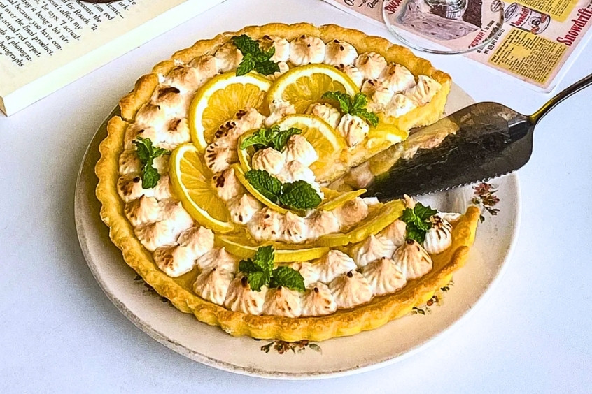 Miếng bánh Key Lime Pie truyền thống với lớp kem chanh mịn màng, màu vàng nhạt, nằm trên đế bánh quy giòn