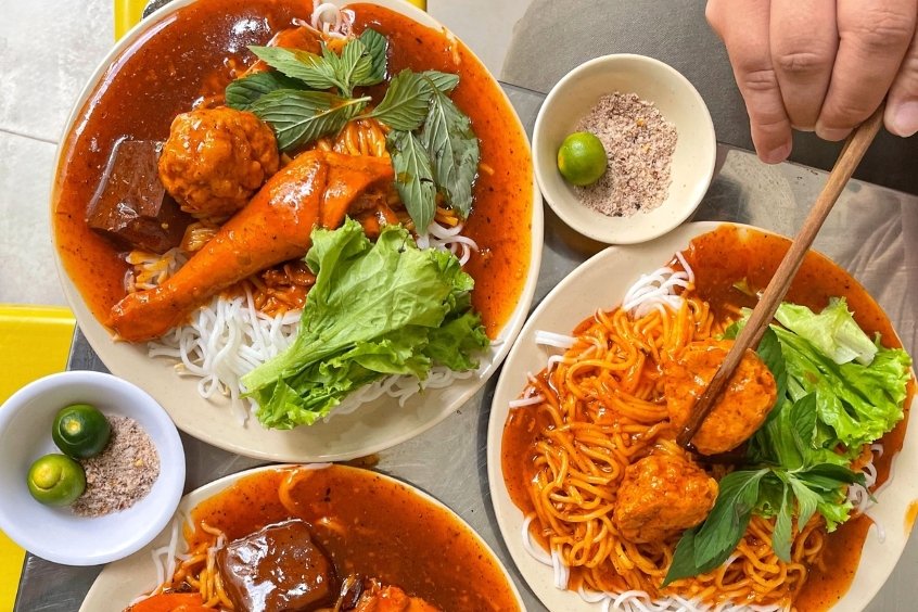 Bánh tầm cay Cà Mau hấp dẫn với sợi bánh mềm dai, phủ lớp nước cà ri đỏ sánh và hành phi thơm lừng, tạo nên hương vị cay nồng đặc trưng miền Tây