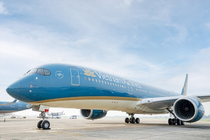 Vietnam Airlines đang đỗ tại sân bay, nổi bật với logo hoa sen đặc trưng