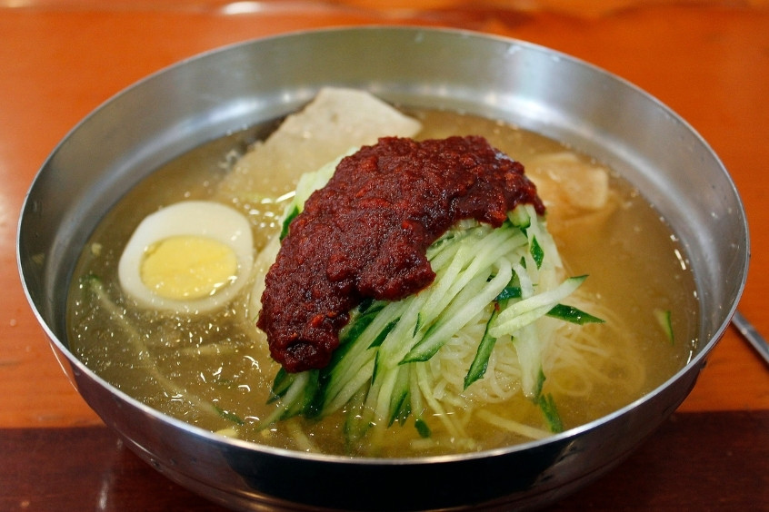 Bát Milmyeon truyền thống với mì sợi vàng, trứng luộc, dưa chuột và thịt bò trong nước dùng lạnh