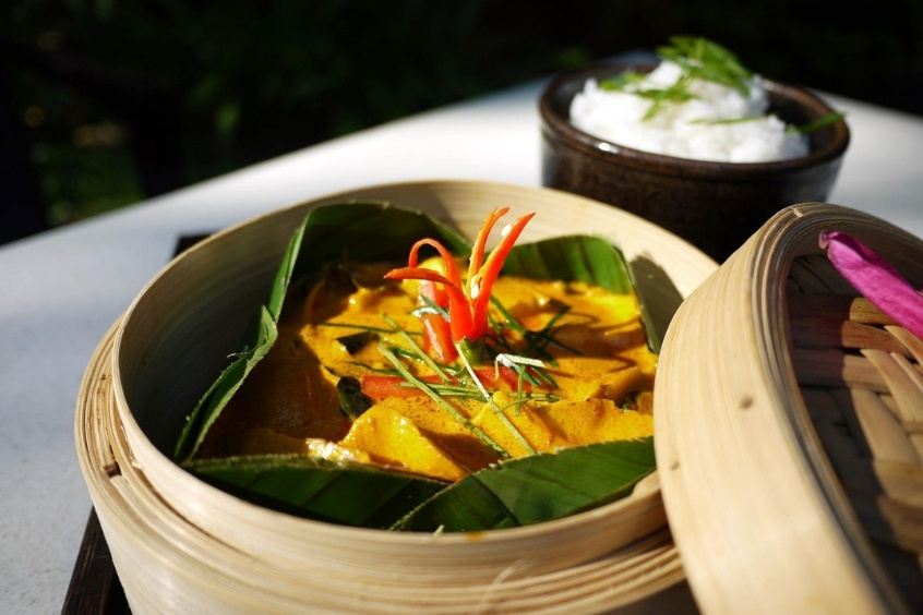 Món cá hấp Amok bày trí trong lá chuối với màu sắc hấp dẫn và hương vị đặc trưng.