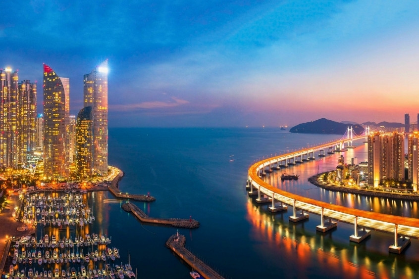 Thành phố Busan về đêm với những tòa nhà chọc trời rực rỡ ánh đèn, cầu Gwangan lấp lánh vắt ngang biển