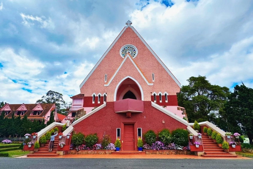 Nhà thờ Domaine de Marie Đà Lạt với kiến trúc cổ điển kiểu Pháp, nổi bật với màu hồng đặc trưng và mái ngói tam giác