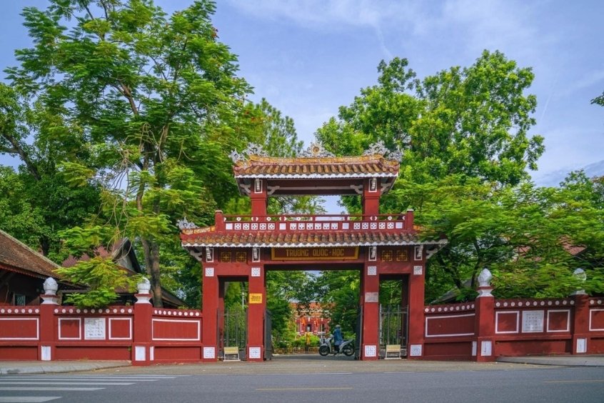 Hình ảnh cổng Trường Quốc Học Huế với kiến trúc cổ điển và màu đỏ nổi bật