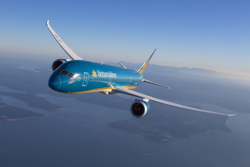 Chiếc máy bay màu xanh và trắng của hãng hàng không Vietnam Airlines đang bay trên bầu trời xanh