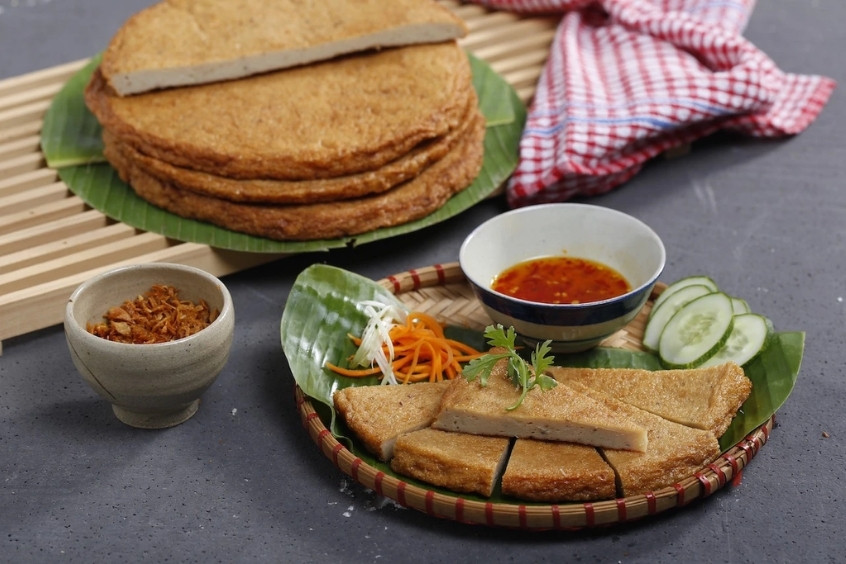 Miếng chả cá chiên vàng giòn hấp dẫn được bày trên đĩa cùng rau sống và nước chấm