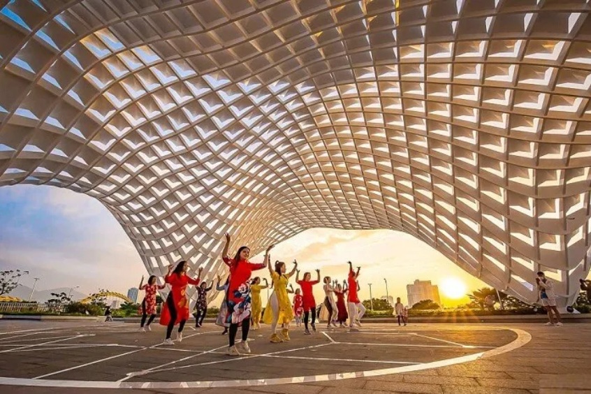 Khoảnh khắc giao thoa tuyệt đẹp giữa nét đẹp truyền thống Áo dài Việt Nam và kiến trúc hiện đại của công viên APEC Đà Nẵng dưới ánh hoàng hôn rực rỡ.