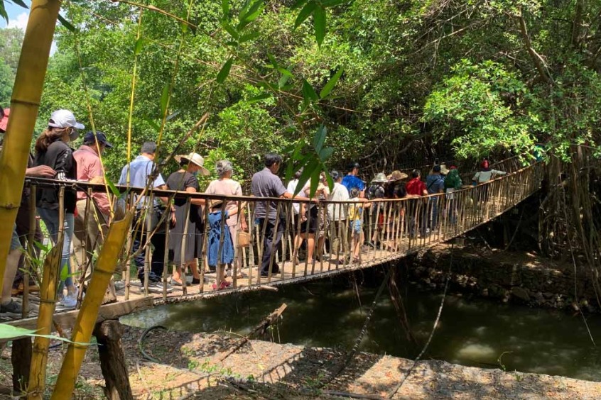 Du khách check-in trên cầu treo gỗ vắt ngang dòng suối Hoa