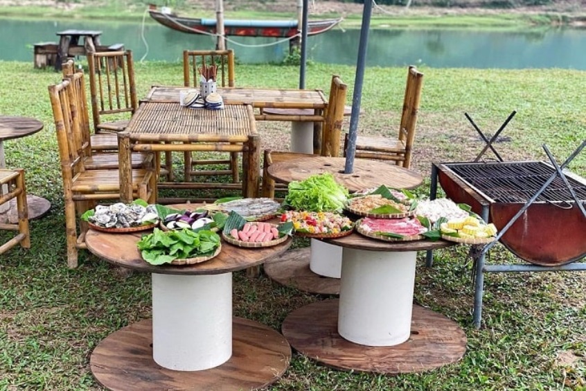 Bàn tiệc BBQ thịnh soạn được bày trí bắt mắt trước cửa lều Glamping vào buổi tối