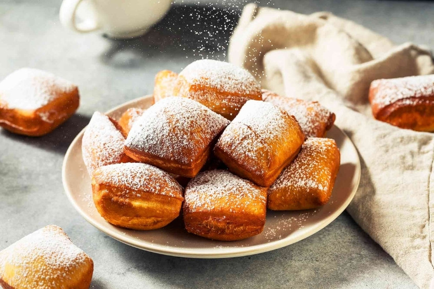 Đĩa bánh rán Beignets vàng giòn phủ lớp đường bột trắng tinh tế