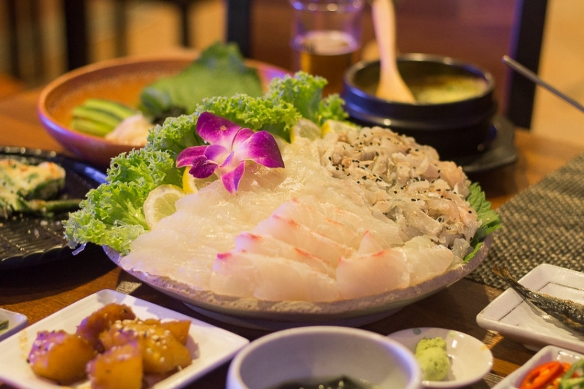 Những lát sashimi cá bơn thái mỏng, trắng trong, được xếp gọn gàng trên đá bào và trang trí với tía tô, hoa cúc