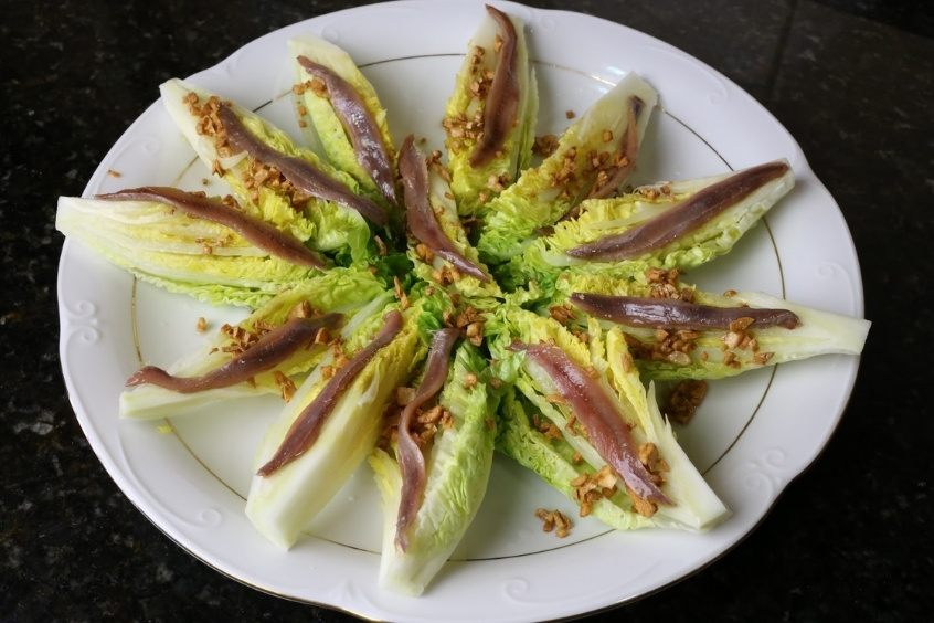 Đĩa Cogollos al ajillo với lá xà lách non, tỏi phi vàng ruộm và cá cơm muối